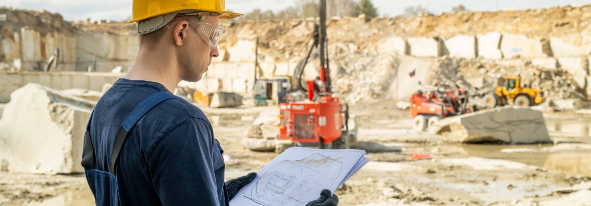 Young builder in workwear holding sketch of construction