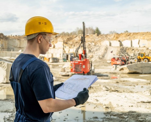 Young builder in workwear holding sketch of construction