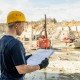 Young builder in workwear holding sketch of construction