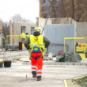 Rear view of male builder construction worker on building site wearing hard hat and hi-vis vest