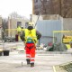 Rear view of male builder construction worker on building site wearing hard hat and hi-vis vest